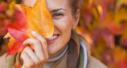 woman signifies changing seasons with autumn leaf